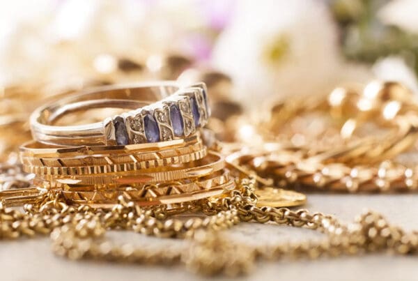 Protecting Your Valuables - Closeup View of Gold Rings with Diamonds Laying on Top of Gold Chains
