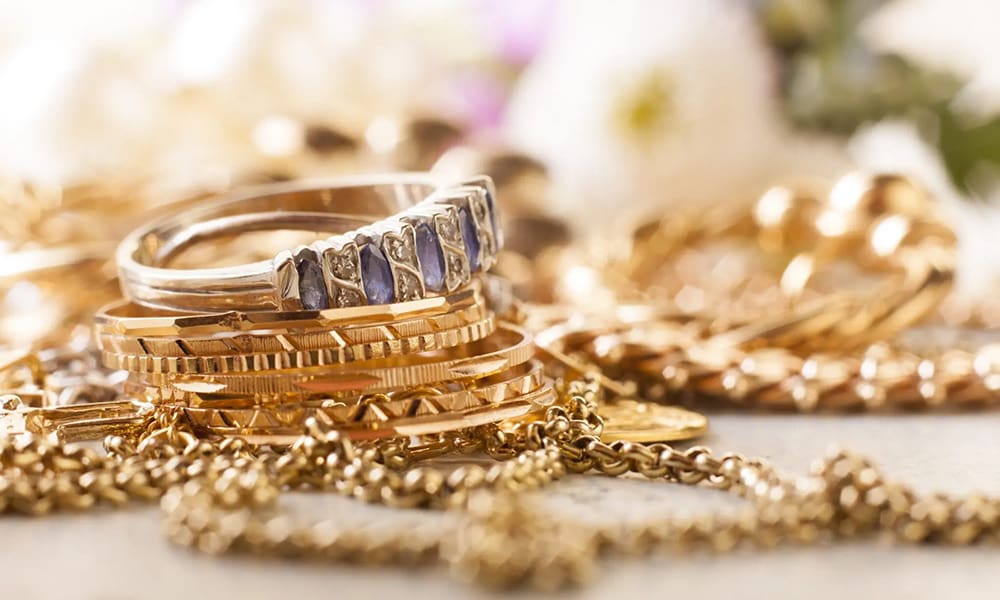 Protecting Your Valuables - Closeup View of Gold Rings with Diamonds Laying on Top of Gold Chains